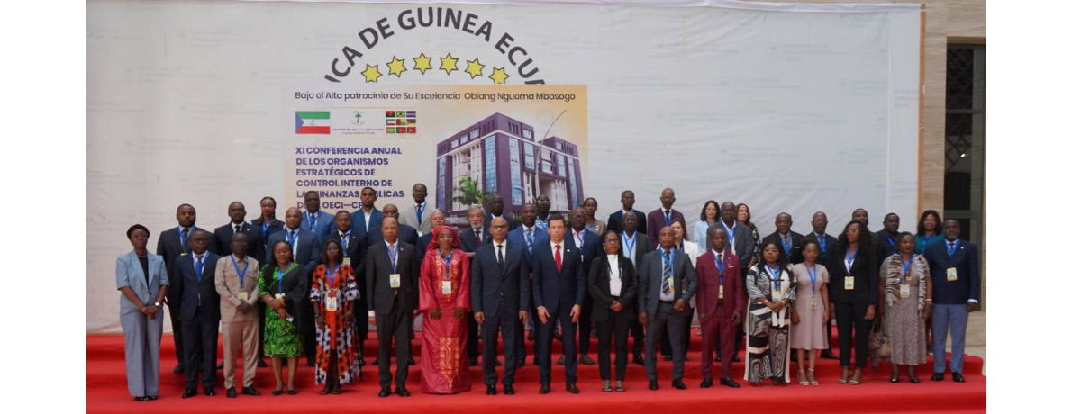 Foto de grupo dos participantes na Conferência posando em frente ao cartaz da conferência