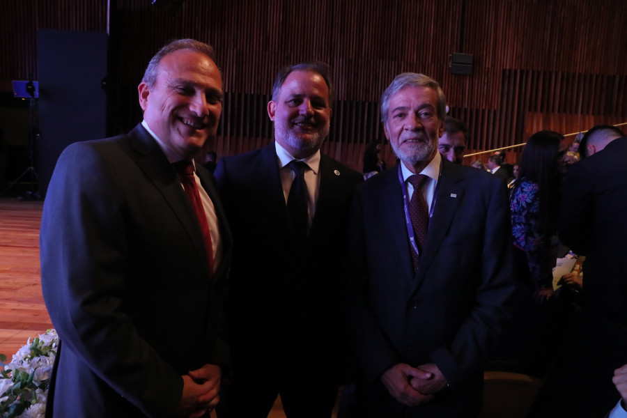 Três indivíduos a posar sorridentes no auditório do congresso. Um deles é o Inspetor-Geral