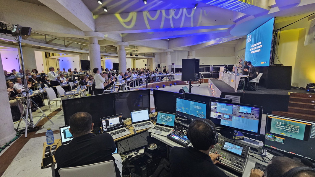 Panorâmica da sala com vários participantes e oradores sentados