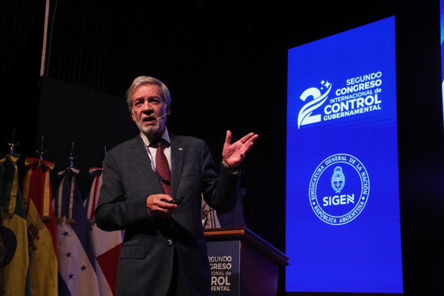 Inspetor-Geral a discursar à frente de várias bandeiras e do cartaz do congresso
