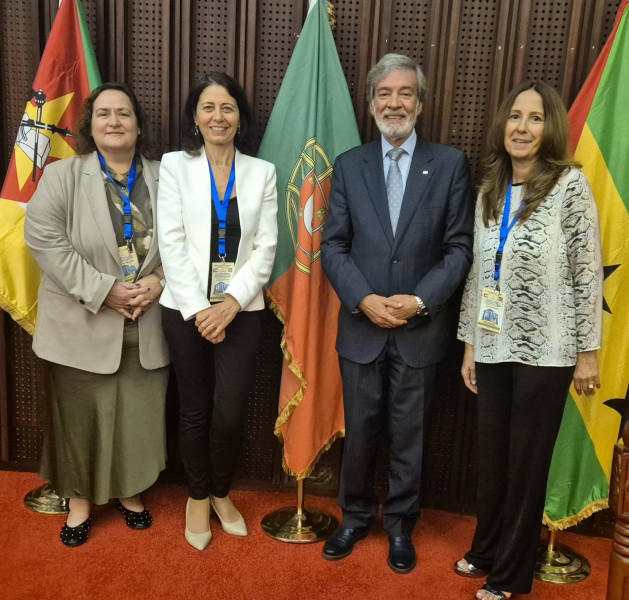 Os quatro elementos da delegação portuguesa a posar à frente de três bandeiras, entre as quais a portuguesa