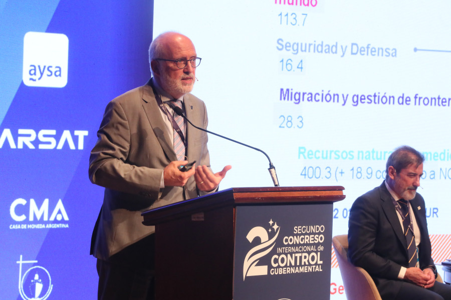 Orador no palco durante uma apresentação projetada no fundo da imagem