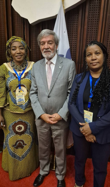 Três representantes das delegações da Guiné Equatorial, de Portugal e de Cabo Verde posam com 1 bandeira atrás de si