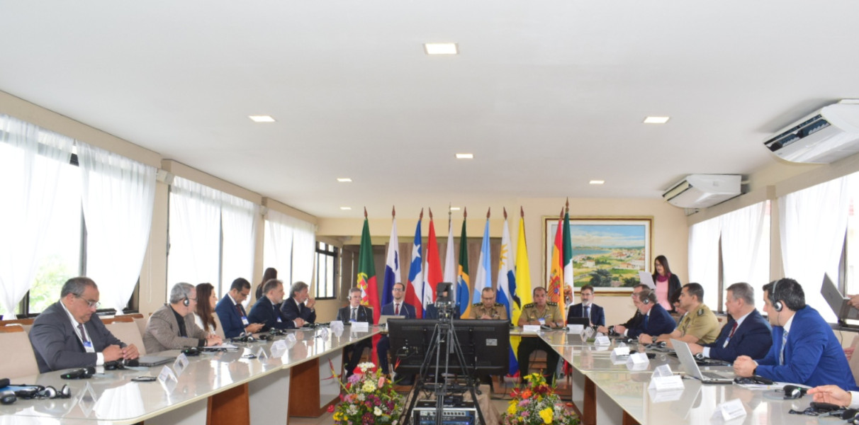Vista panorâmica da mesa de reunião numa sala com vários participantes sentados