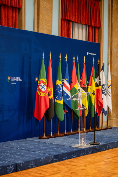 Bandeiras de Portugal e dos países membros da CPLP dispostas num palco.