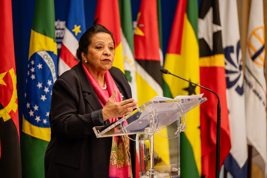 Oradora a discursar à frente das bandeiras dos países membros da CPLP.