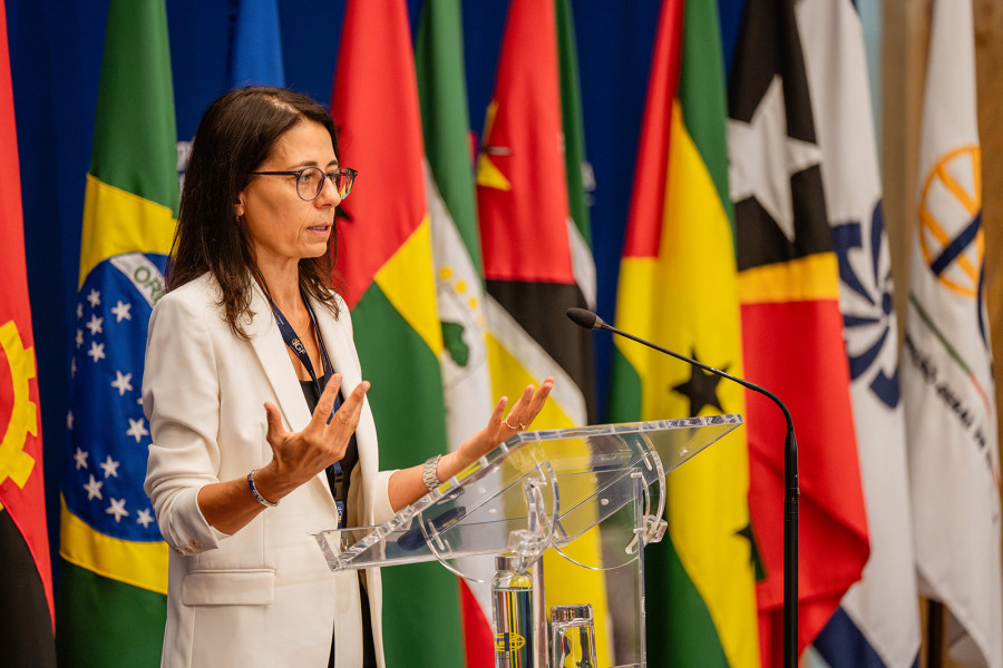 Subinspetora-Geral da IGF a discursar à frente das bandeiras dos países membros da CPLP.