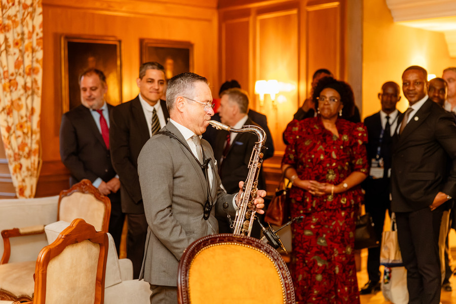 Músico a tocar saxofone para os participantes da conferência durante um momento cultural.