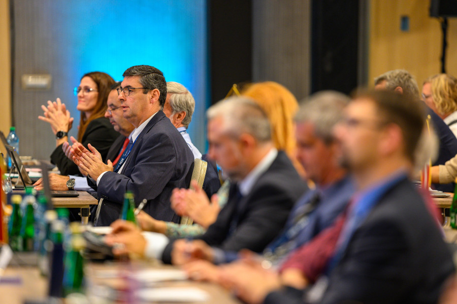 Momento em que os delegados aplaudem durante a 33rd Homologues Group Meeting. Em destaque os 3 membros da delegação de Portugal