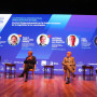 Painel de discussão com 4 oradores sentados no palco durante o congresso