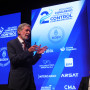 Inspetor-Geral a discursar à frente do cartaz do congresso