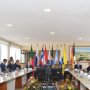 Vista panorâmica da mesa de reunião numa sala com vários participantes sentados