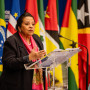 Oradora a discursar à frente das bandeiras dos países membros da CPLP.