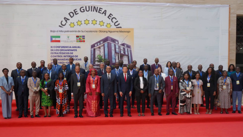 Foto de grupo dos participantes na Conferência posando em frente ao cartaz da conferência